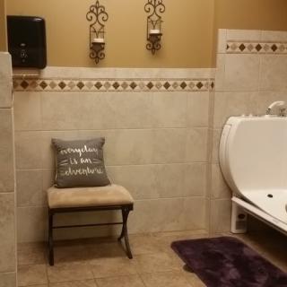 A tastefully decorated bathroom with a cushioned bench and wall art.