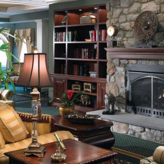 A cozy living room with a stone fireplace and a wooden bookshelf.