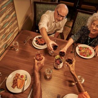 A group of people toasting with wine during a dinner gathering.