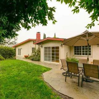 A cozy backyard with a patio, outdoor dining set, and green lawn.