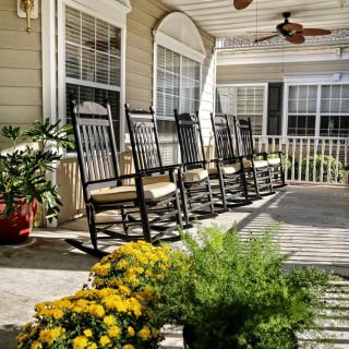A serene porch setting with rocking chairs and vibrant plants.