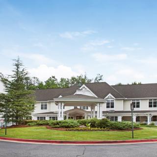A large residential building with landscaped surroundings and a clear blue sky.