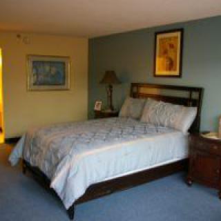 A cozy bedroom with a bed, nightstand, and artwork on the walls.
