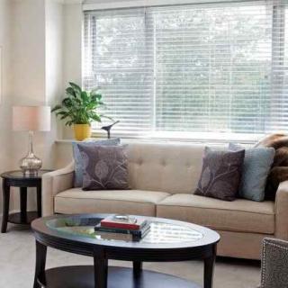 A cozy living room with a sofa, coffee table, and a lamp by the window.