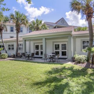 A beautiful house with palm trees and a spacious backyard patio on a sunny day.