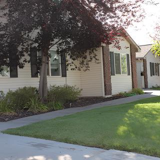 A residential house with a well-maintained lawn and surrounding trees.