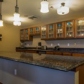 A modern kitchen featuring granite countertops, wooden cabinets, and stylish lighting fixtures.
