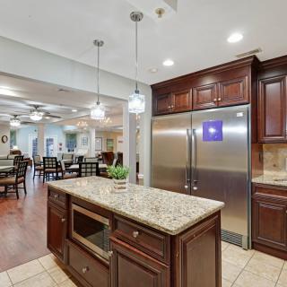 A modern kitchen featuring an island with granite countertops, stainless steel appliances, and wooden cabinets.