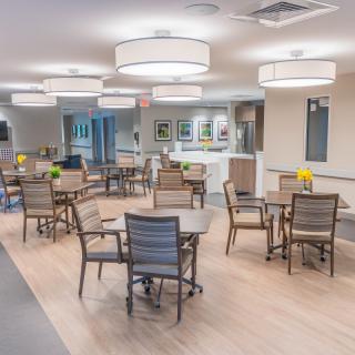 A modern dining area with several tables and chairs, featuring stylish lighting and a clean interior design.