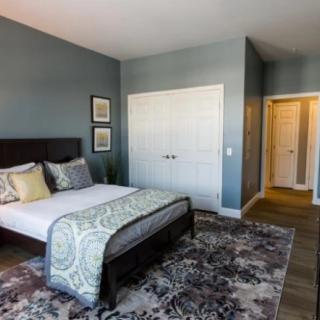 A modern bedroom with neutral colors, featuring a double bed, patterned carpet, and stylish decor.