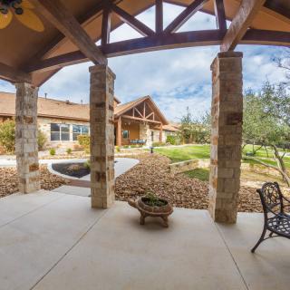 A spacious patio with stone pillars overlooks a landscaped garden.