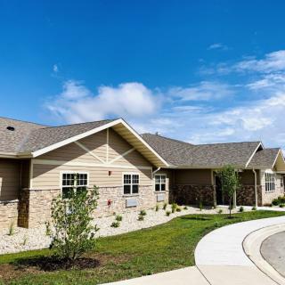 A suburban residential house with well-maintained landscaping under a clear blue sky.