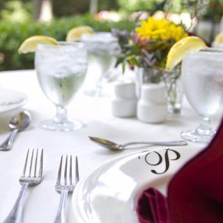 A beautifully arranged outdoor table setting with elegant glassware and silverware, complemented by fresh flowers and lemon garnishes.