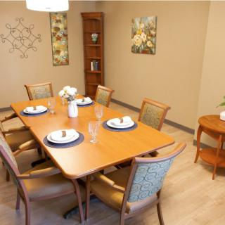 A well-decorated dining room with a wooden table set for a meal, surrounded by upholstered chairs and adorned with wall art and decorations.