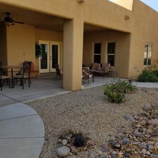 A covered patio area with outdoor seating and desert-style landscaping.