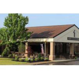 A quaint restaurant building with a landscaped garden and trees.