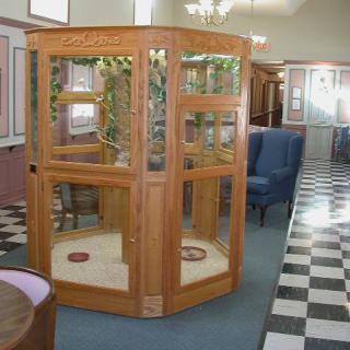 A vintage wooden phone booth situated in an interior space with checkered flooring.