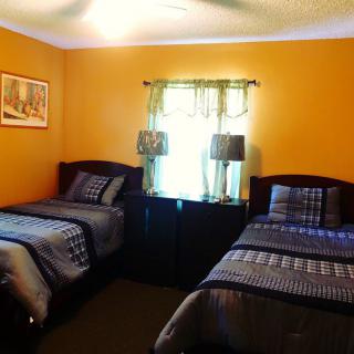 A cozy bedroom with two twin beds and orange walls.