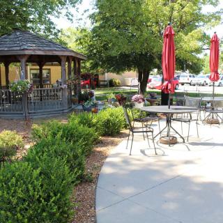 A scenic outdoor patio with a gazebo and seating areas surrounded by lush landscaping.