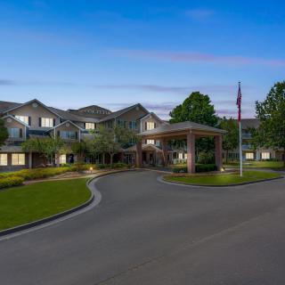 A well-maintained residential building with a circular driveway and landscaped surroundings in the evening.