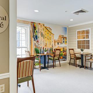 A cozy cafe interior with a mural and neatly arranged seating.