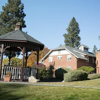 A scenic view of a gazebo and brick building surrounded by trees and grass.