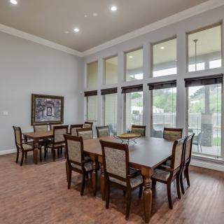A spacious dining area with large windows, multiple tables, and wooden flooring.