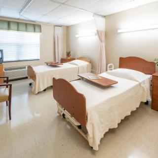 A clean and organized hospital room with two patient beds and essential furniture.