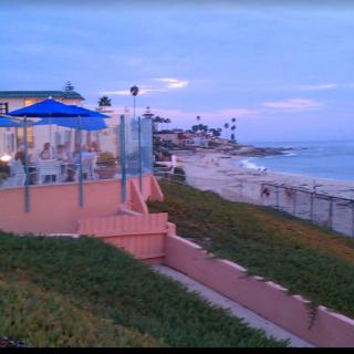 A scenic view of the coastline with buildings and a patio overlooking the ocean at sunset.