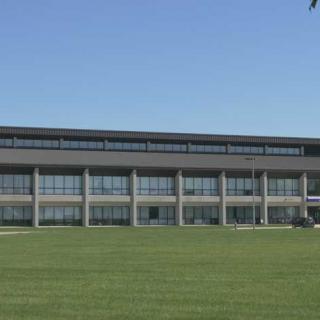A modern building with large windows and a grassy lawn in front.