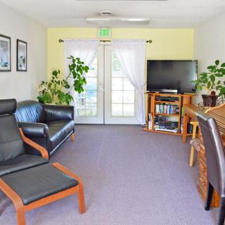 A cozy living room with comfortable seating, plants, and a TV for entertainment.