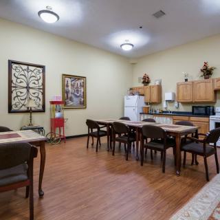 A spacious kitchen and dining area featuring multiple tables and chairs, with wooden cabinets and decorative wall art.