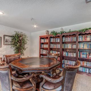 A cozy library room with bookshelves, a round table, and chairs.
