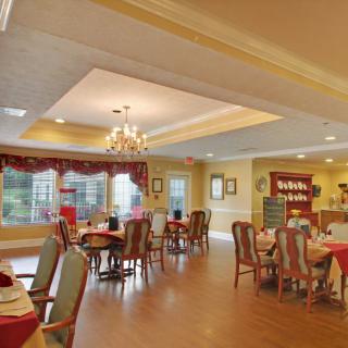 A cozy dining room with elegant chandeliers and well-arranged tables and chairs.
