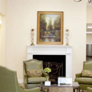 A cozy living room with a fireplace, armchairs, and artwork above the mantel.