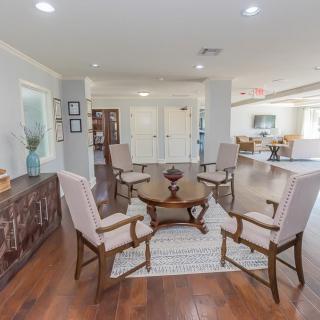 A cozy living room with a circular arrangement of chairs around a wooden table on a rug.