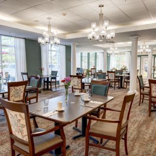 A well-decorated dining room with elegant chandeliers and neatly arranged tables and chairs.