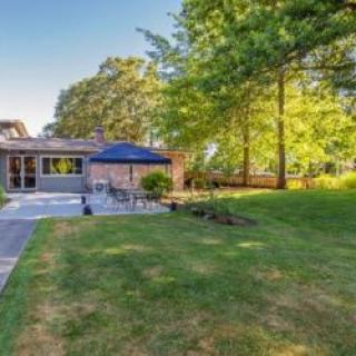 A spacious backyard with a lush lawn, patio area, and surrounding trees, perfect for outdoor relaxation.