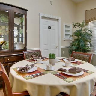 A cozy dining room with a round table set for four, featuring a china cabinet and a decorative plant.