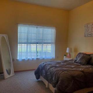 A cozy bedroom with a bed, mirror, and a window letting in natural light.