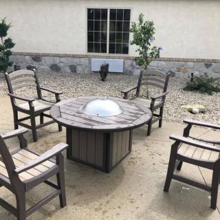 A cozy patio seating area with a circular table and four chairs, set in a backyard.