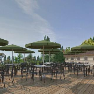 An outdoor patio with multiple tables and chairs under green umbrellas on a sunny day.