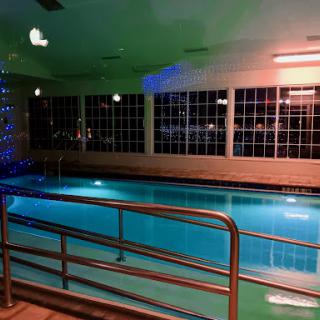 A serene indoor swimming pool illuminated with soft blue and orange lighting.
