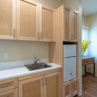 A modern kitchen with wooden cabinets, a sink, and a refrigerator.