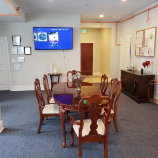 A dining room with a wooden table and chairs, a wall-mounted TV, and decorative elements.