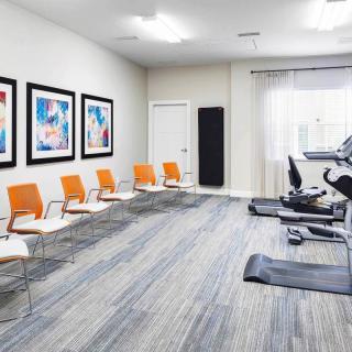 A modern gym interior with exercise equipment and seating area.