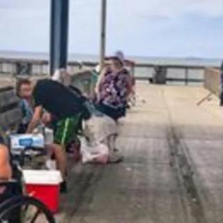 People enjoying a day of fishing on a pier overlooking the ocean.