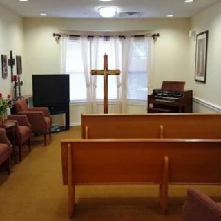 A small chapel with pews, a cross at the front, and an organ in the corner.