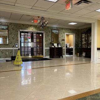 A spacious lobby area with decorative wallpaper, polished flooring, and a reception desk.