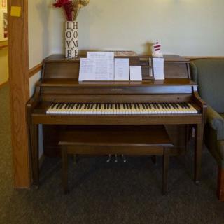A piano with sheet music placed on the stand in a living room setting.